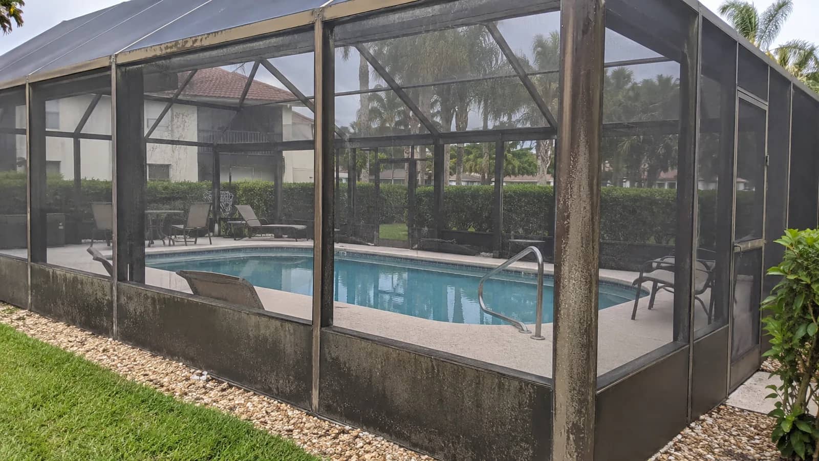 Aluminium pool screen enclosure at a condominium with mildew on the frame and screen panels